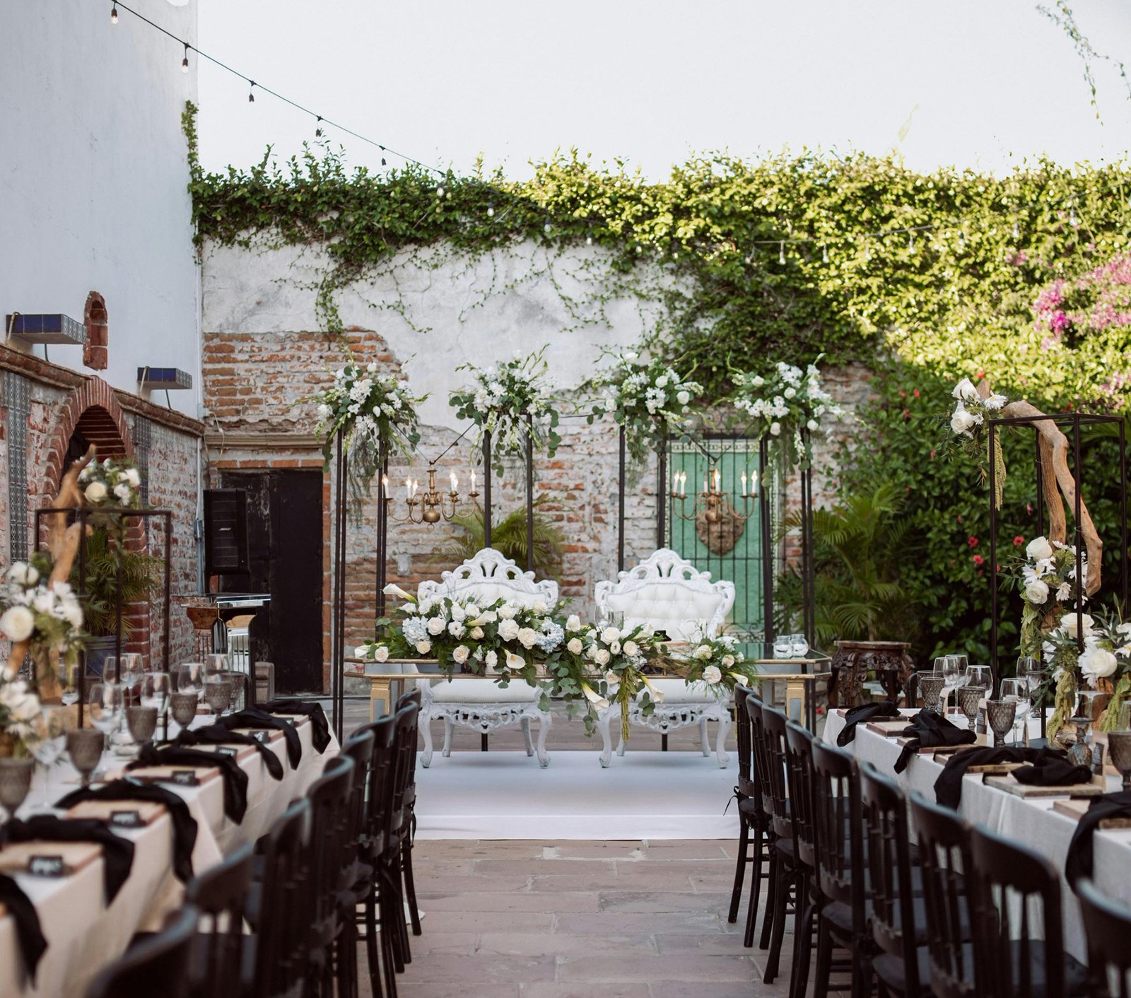 Sweetheart table with lush florals at the head of two rows of tables